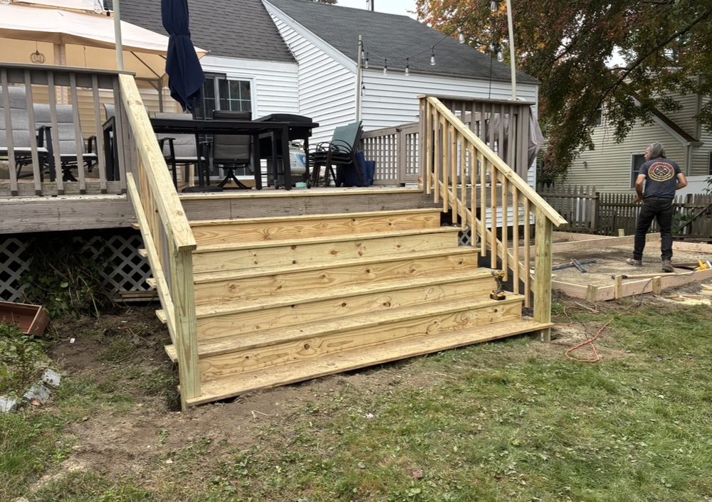 New pressure-treated wood deck stairs and railings built on the back of a Massachusetts home