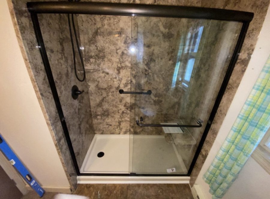 New shower with stone-look wall panels, white base and black framed sliding glass door