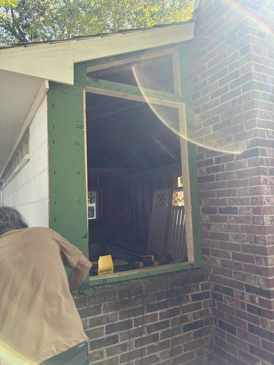 Carpenter framing a new window opening in a brick home exterior